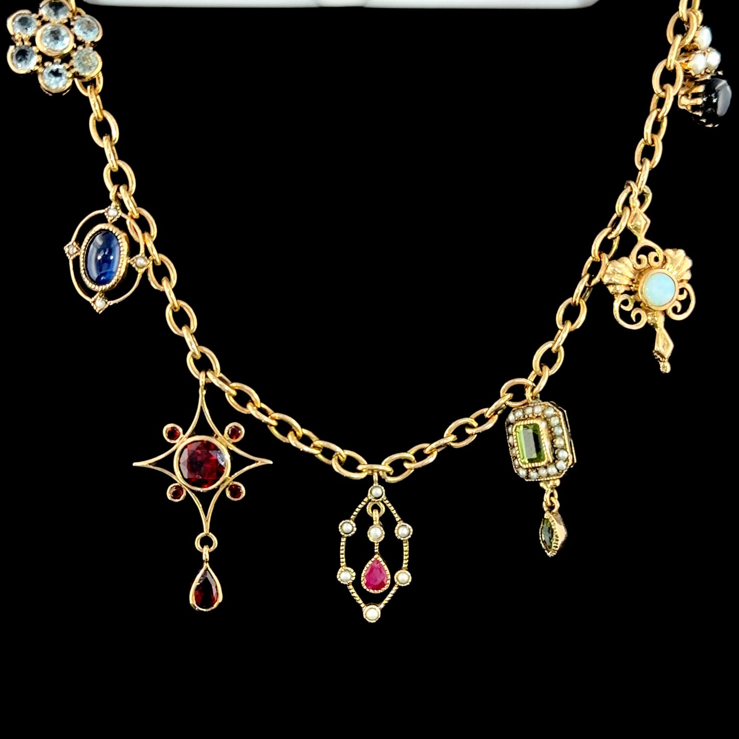 A Spectacular Victorian 9k Yellow Gold Charm Bracelet Having Sapphire, Pearl, Garnet, Aqua & Peridot Articulated Charms. 8” in Length.