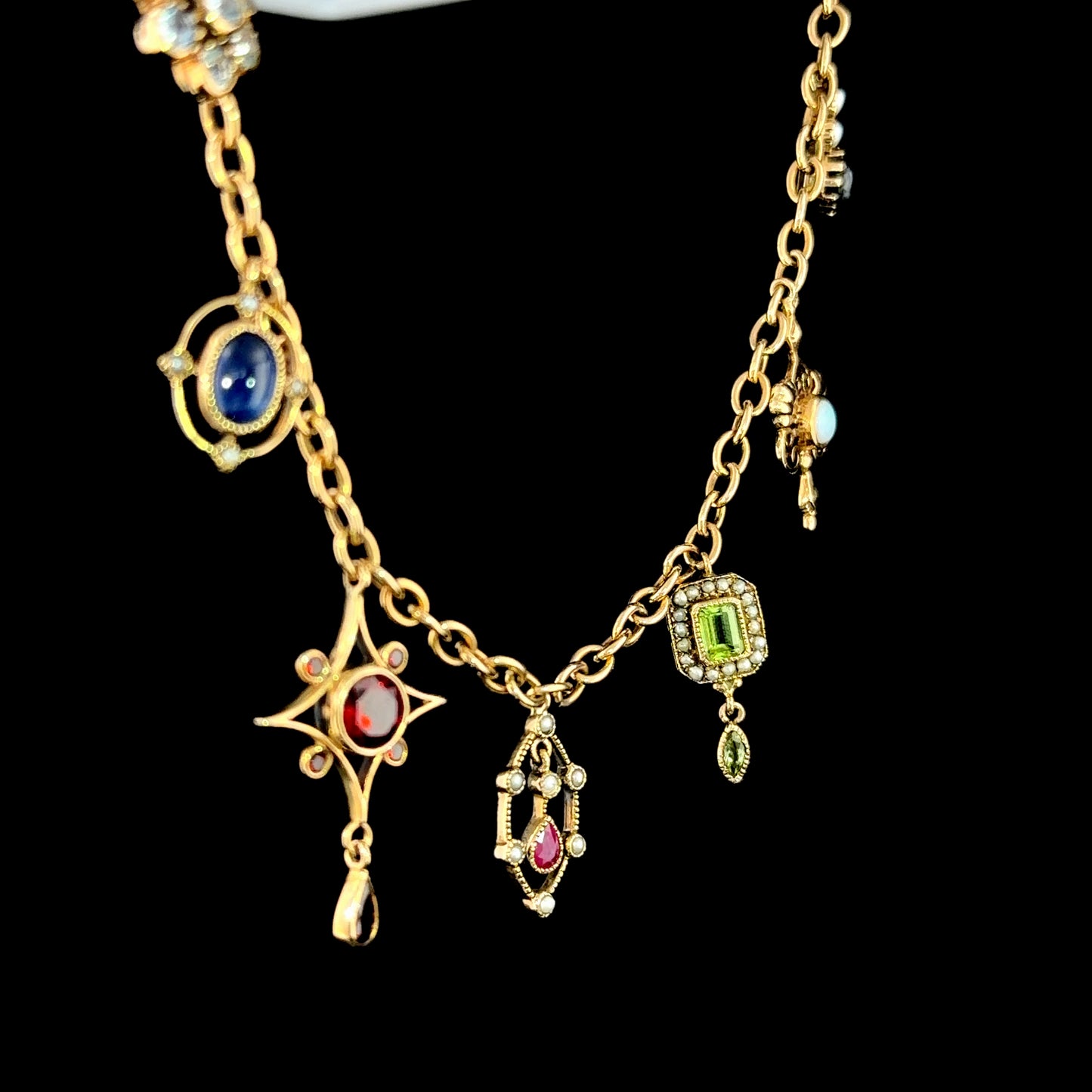 A Spectacular Victorian 9k Yellow Gold Charm Bracelet Having Sapphire, Pearl, Garnet, Aqua & Peridot Articulated Charms. 8” in Length.