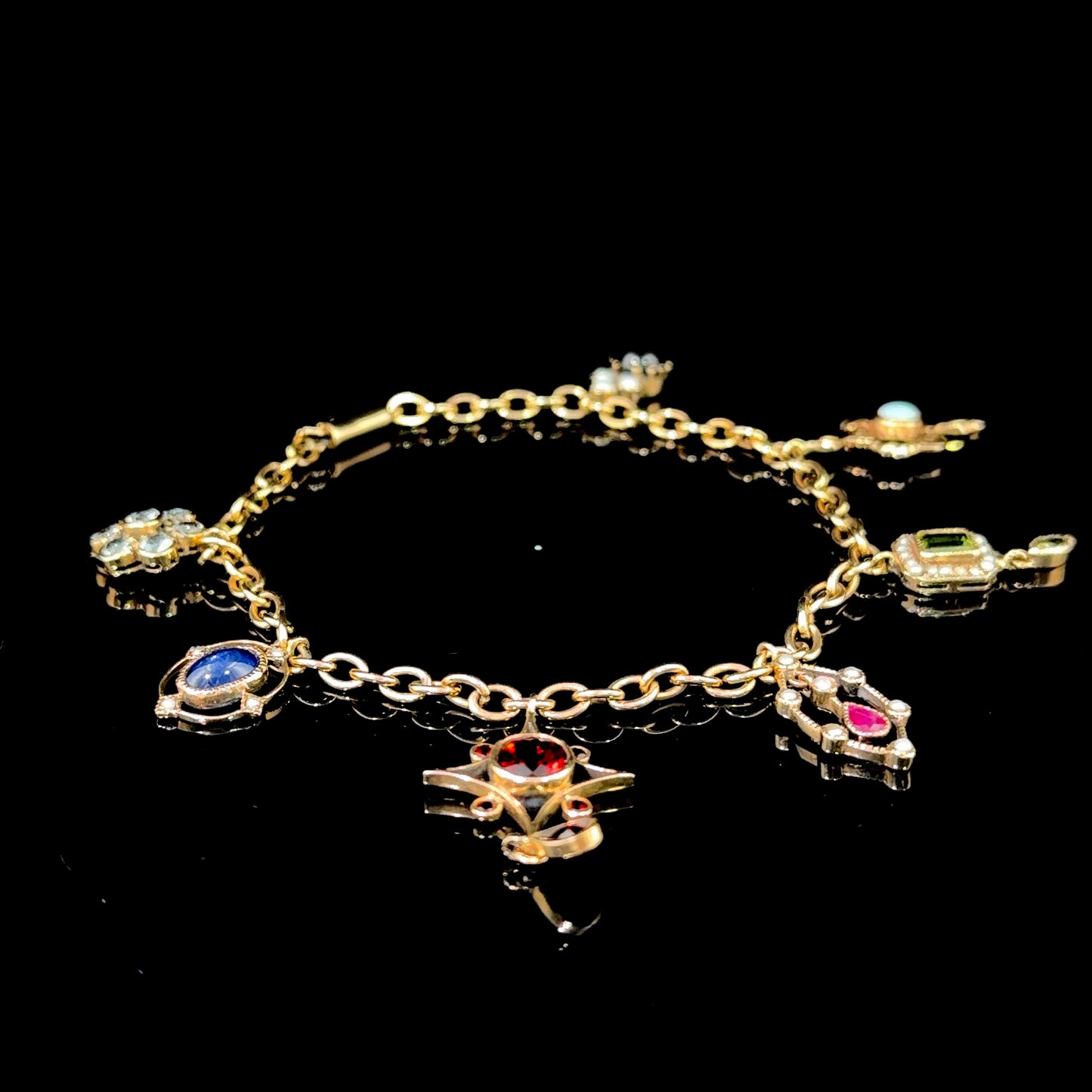 A Spectacular Victorian 9k Yellow Gold Charm Bracelet Having Sapphire, Pearl, Garnet, Aqua & Peridot Articulated Charms. 8” in Length.