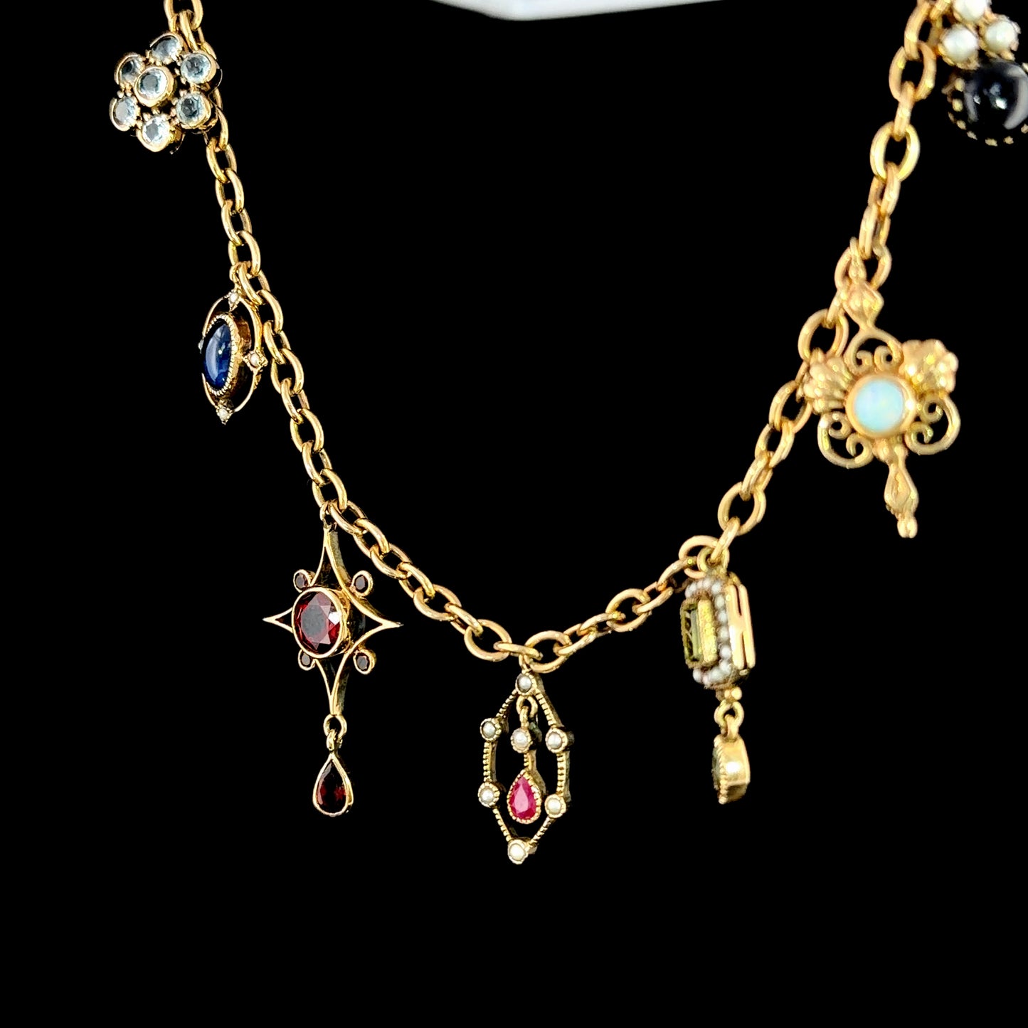 A Spectacular Victorian 9k Yellow Gold Charm Bracelet Having Sapphire, Pearl, Garnet, Aqua & Peridot Articulated Charms. 8” in Length.