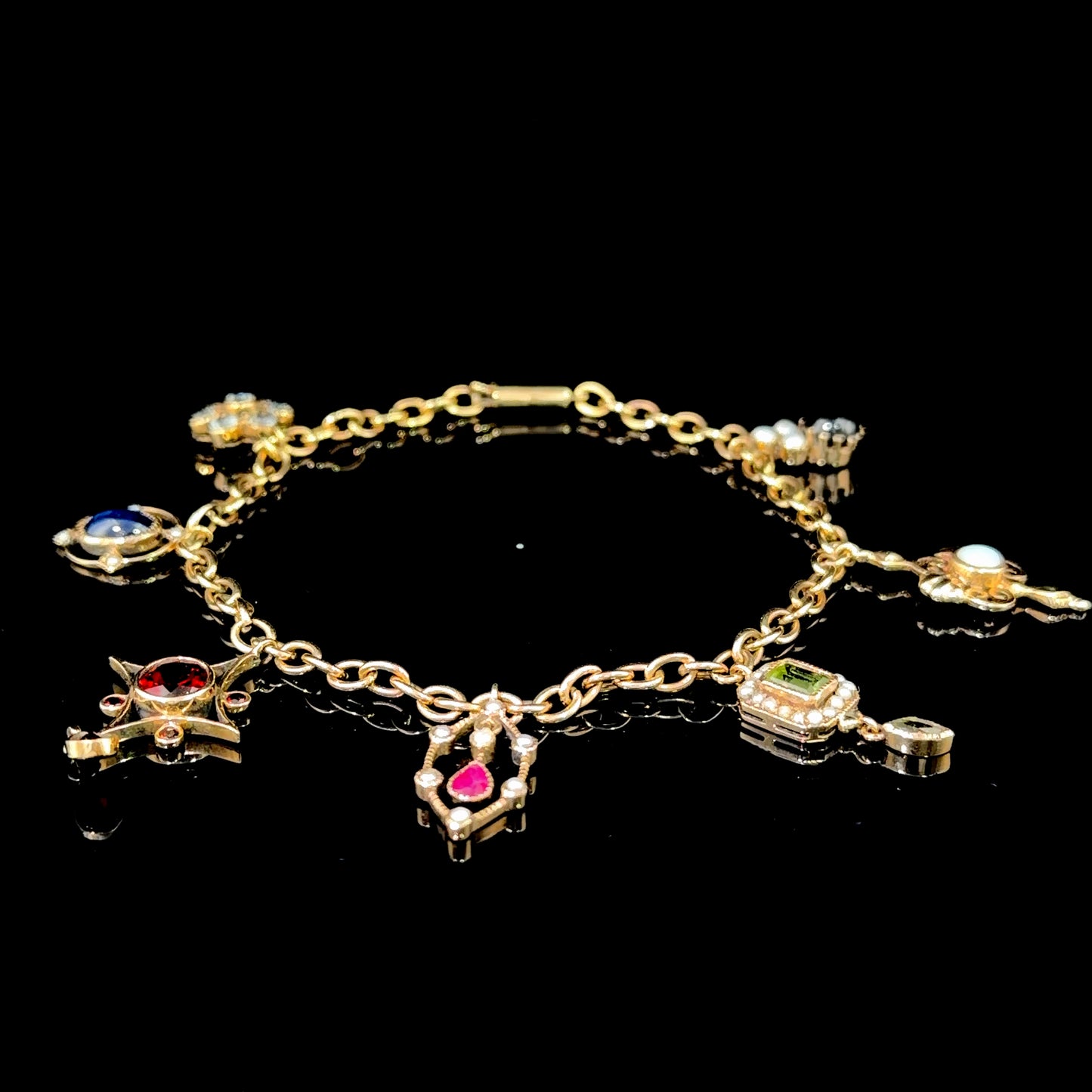 A Spectacular Victorian 9k Yellow Gold Charm Bracelet Having Sapphire, Pearl, Garnet, Aqua & Peridot Articulated Charms. 8” in Length.