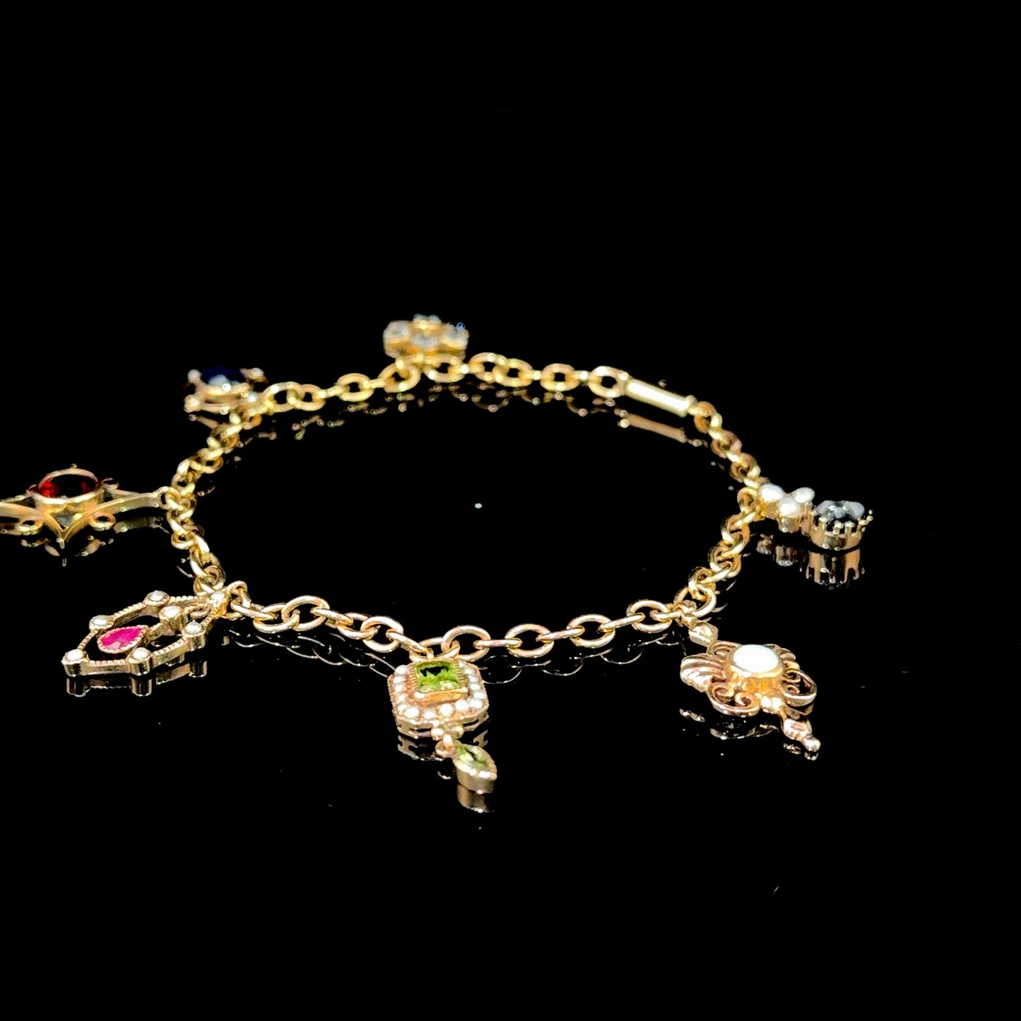A Spectacular Victorian 9k Yellow Gold Charm Bracelet Having Sapphire, Pearl, Garnet, Aqua & Peridot Articulated Charms. 8” in Length.